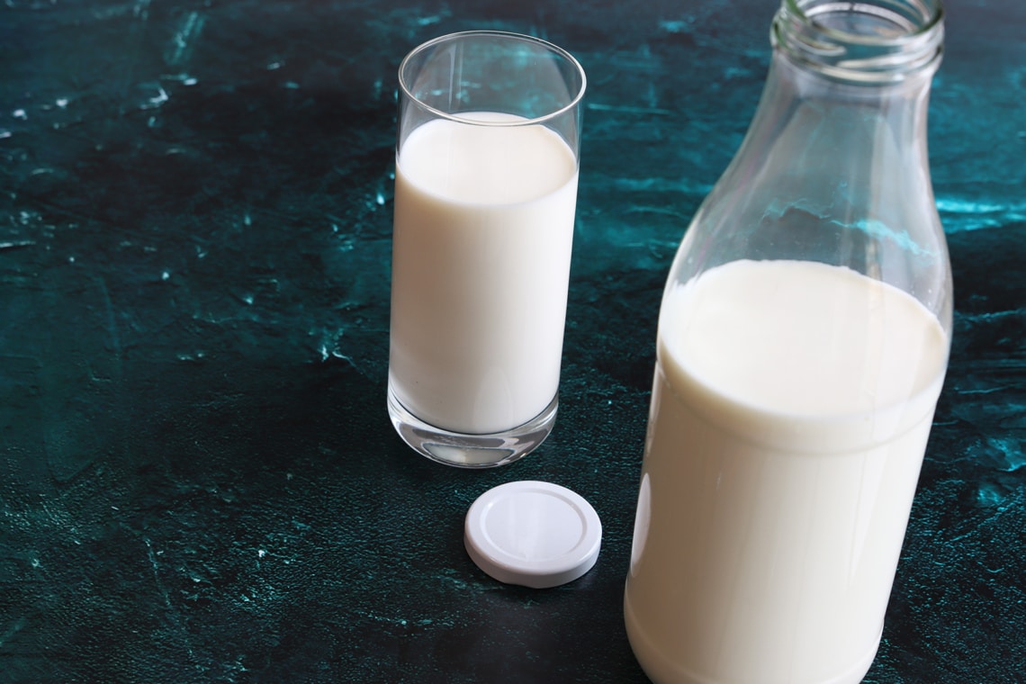 Glas und Flasche mit Milch auf Tisch