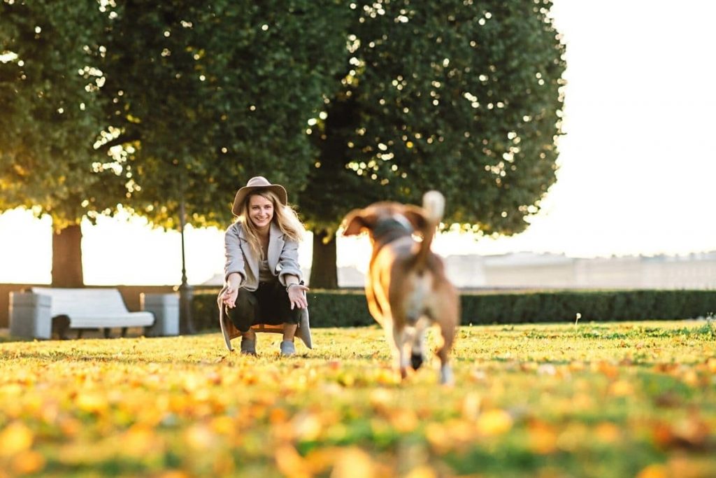 Frau ruft Hund im Park zurück