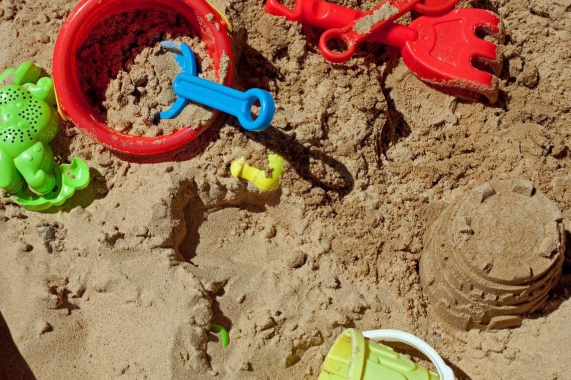 Förmchen, Eimer und kleine Sandbauwerke in Sandkasten