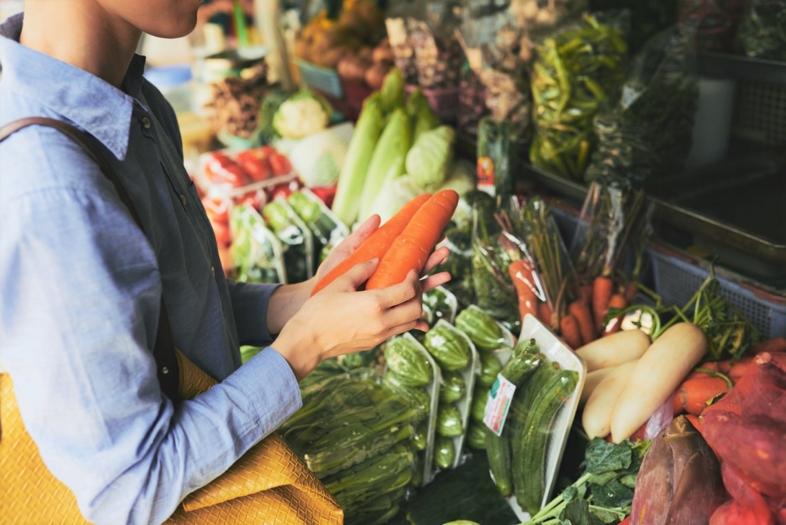 Frau testet Möhren im Supermarkt