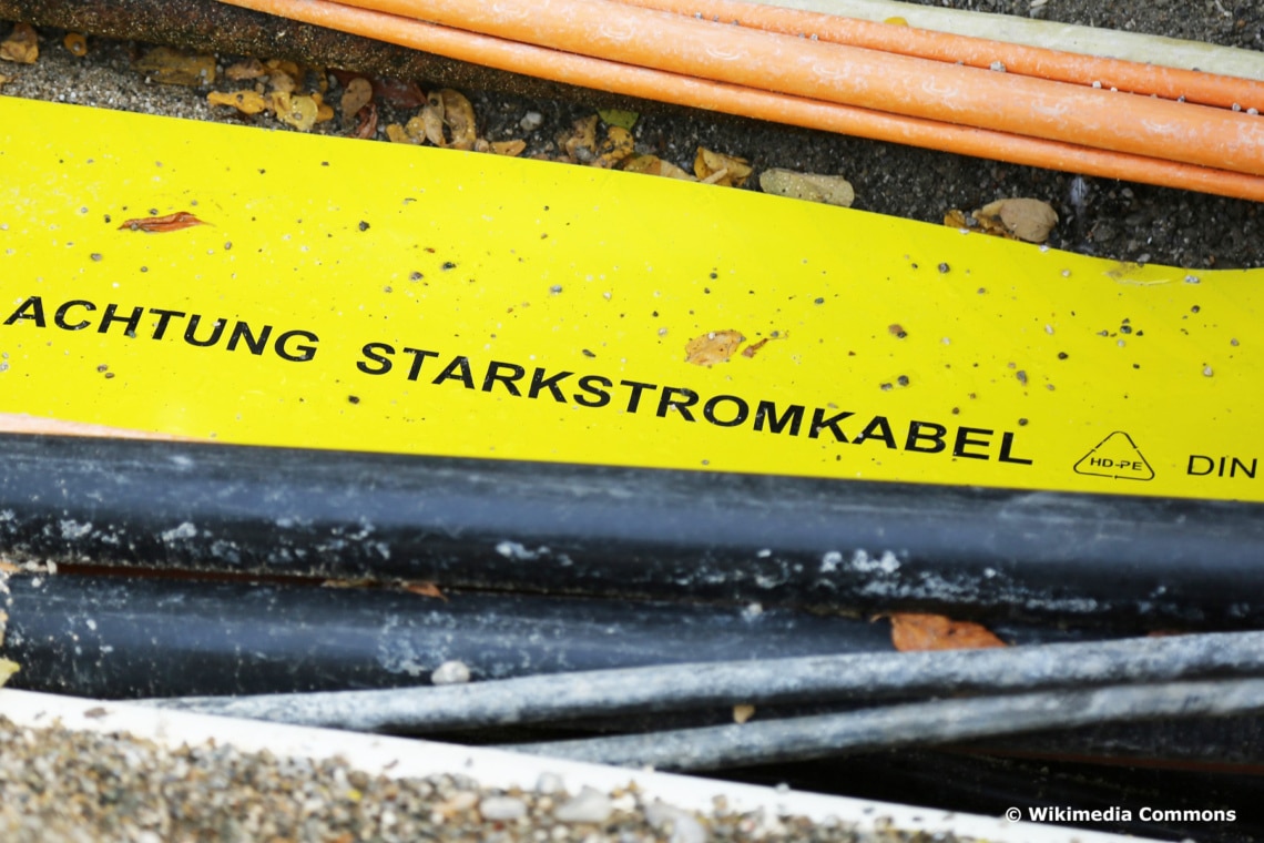 Gelbes Warnband mit der Aufschrift "Achtung Starkstromkabel" an Erdkabel