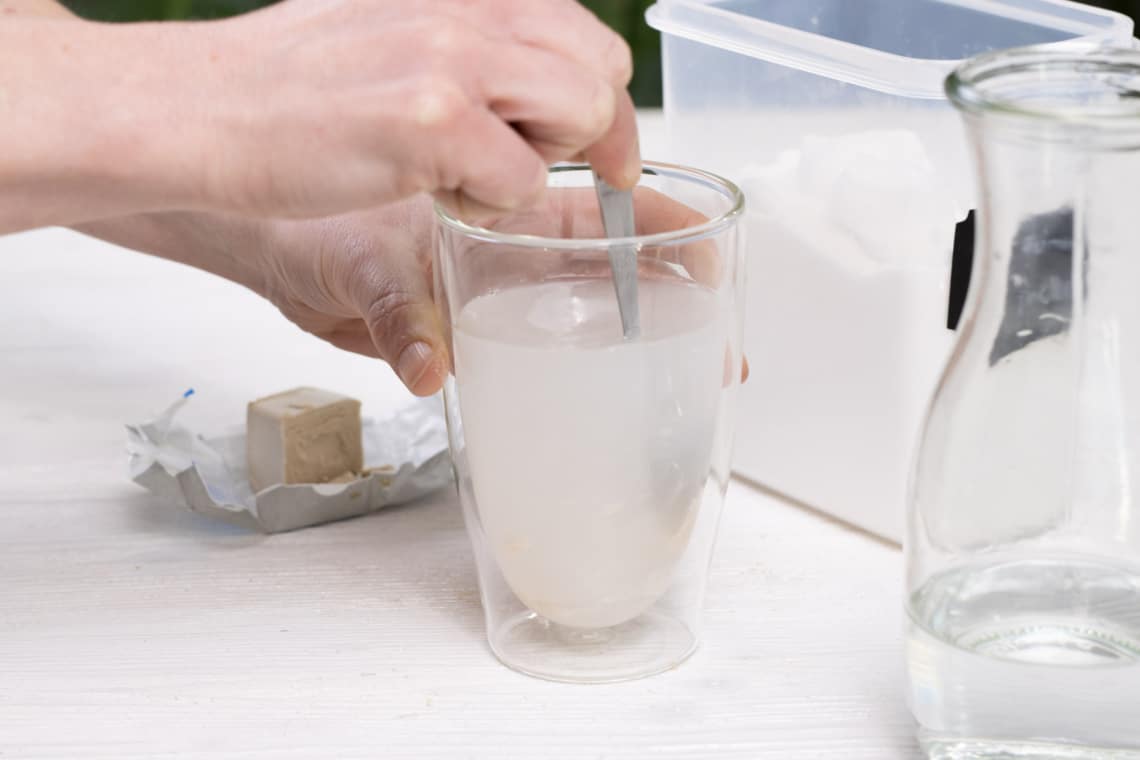 Hefe in Wasser auflösen durch rühren mit einem Löffel