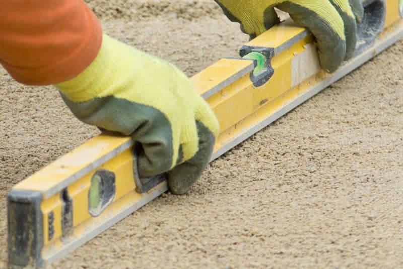 Arbeiter prüft mit Wasserwaage das Gefälle auf dem Boden