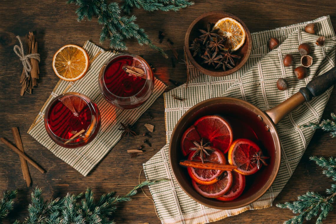 Glühwein im Topf und Gläsern mit Nelken, Zimtstangen und Orange