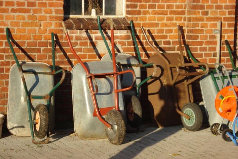 Verschiedene Schubkarren lehnen an Hauswand