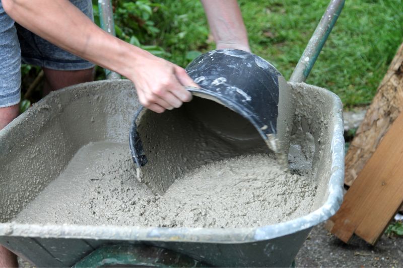 Drainagebeton in einer Schubkarre mit Eimer herausholen