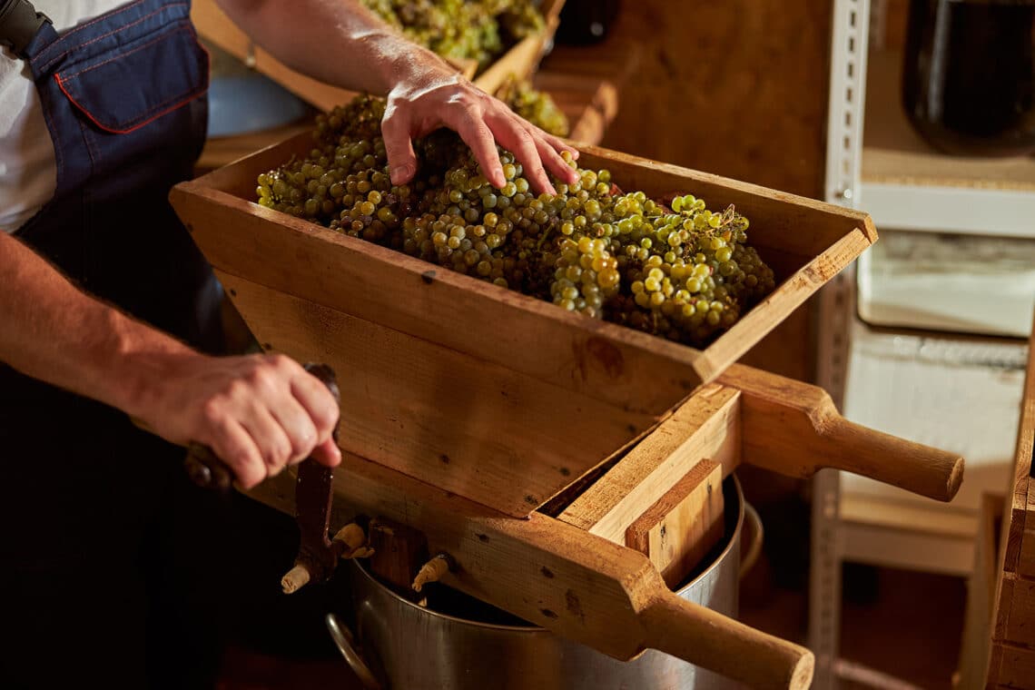 Mann betätigt Weinpresse