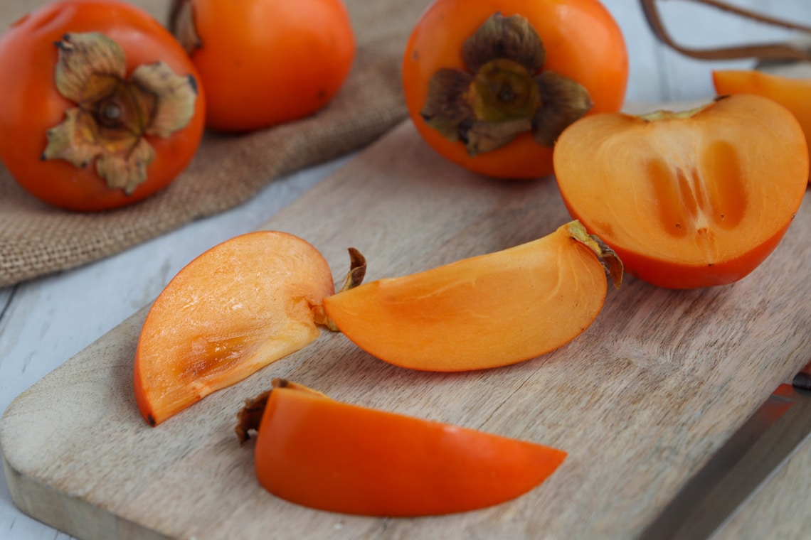 Kaki Frucht aufgeschnitten auf einem Holzbrett